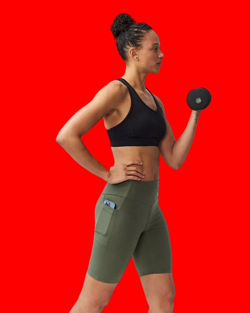 Woman in athletic wear holding a dumbbell against a plain background